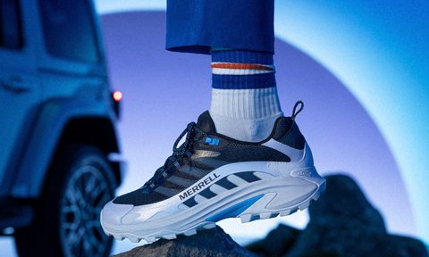 person standing on rock with merrell logo shoes with jeep in background