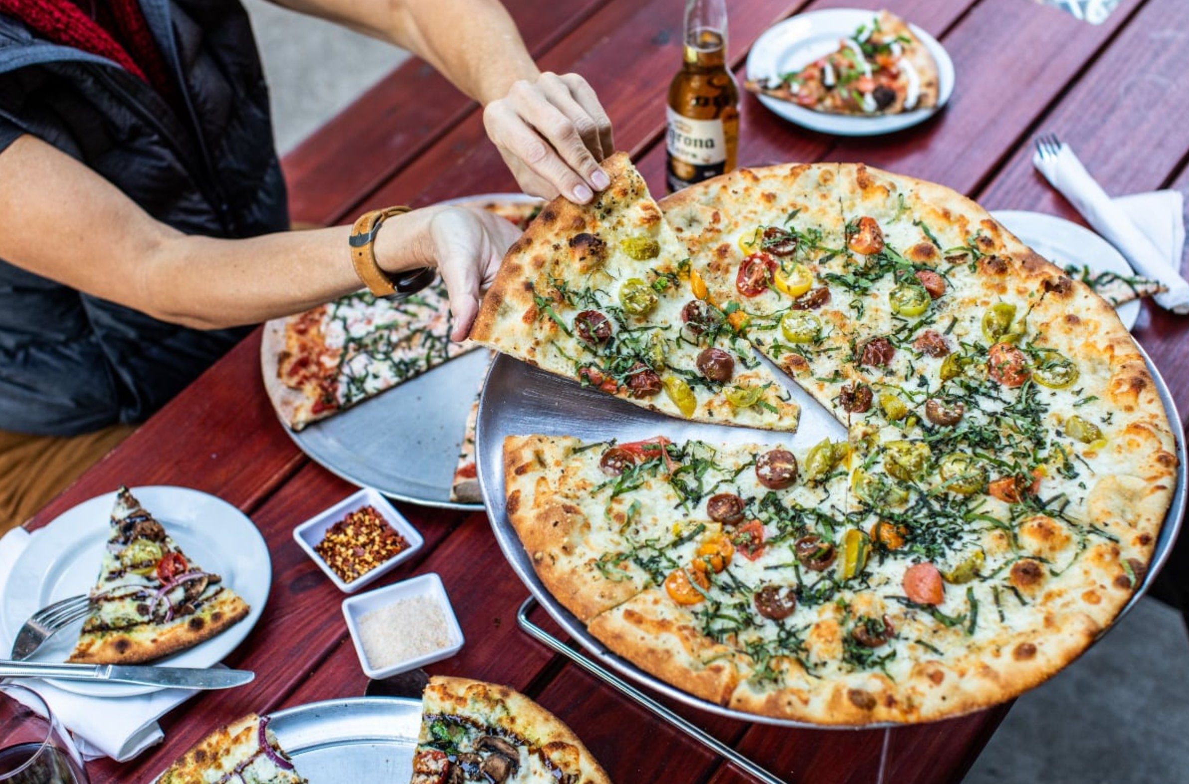 A full pizza with a person removing a single slice