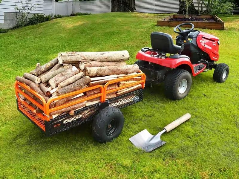 The Vevor 1500 lbs. 15 cu. ft. Steel Dump Cart being hauled by a riding lawn mower.