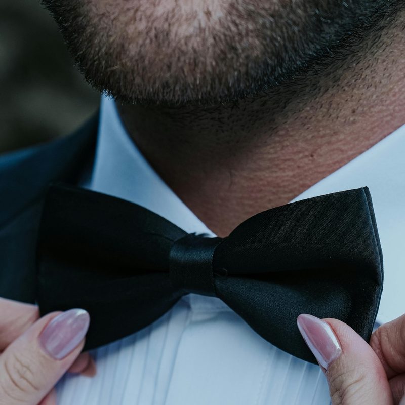 Woman straightening man's bowtie