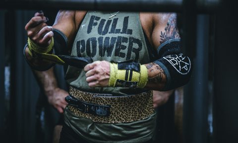 Close-up of a man wearing Full Power shirt putting gloves on wearing training belt gym weightlifting