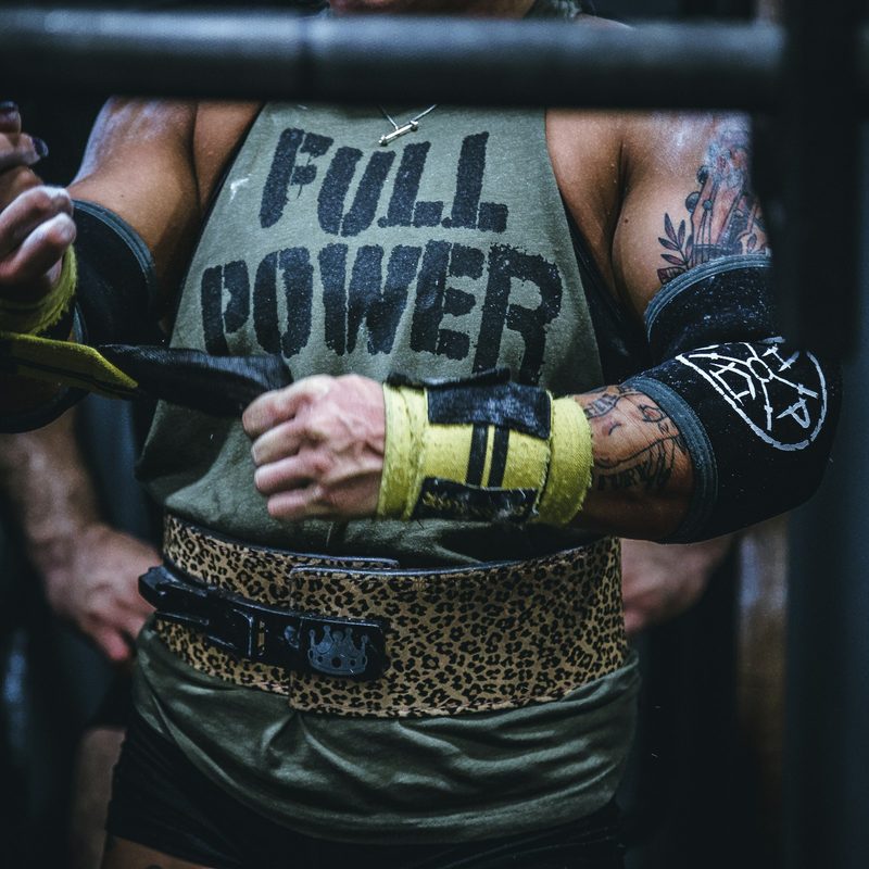 Close-up of a man wearing Full Power shirt putting gloves on wearing training belt gym weightlifting