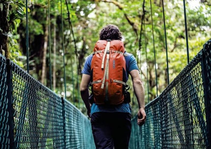 man with an orange backpack walking outside