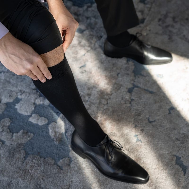 Businessman wearing compression socks. Closeup top view. no face. Pulling up the sock. wearing official office outfit, classic shoes.