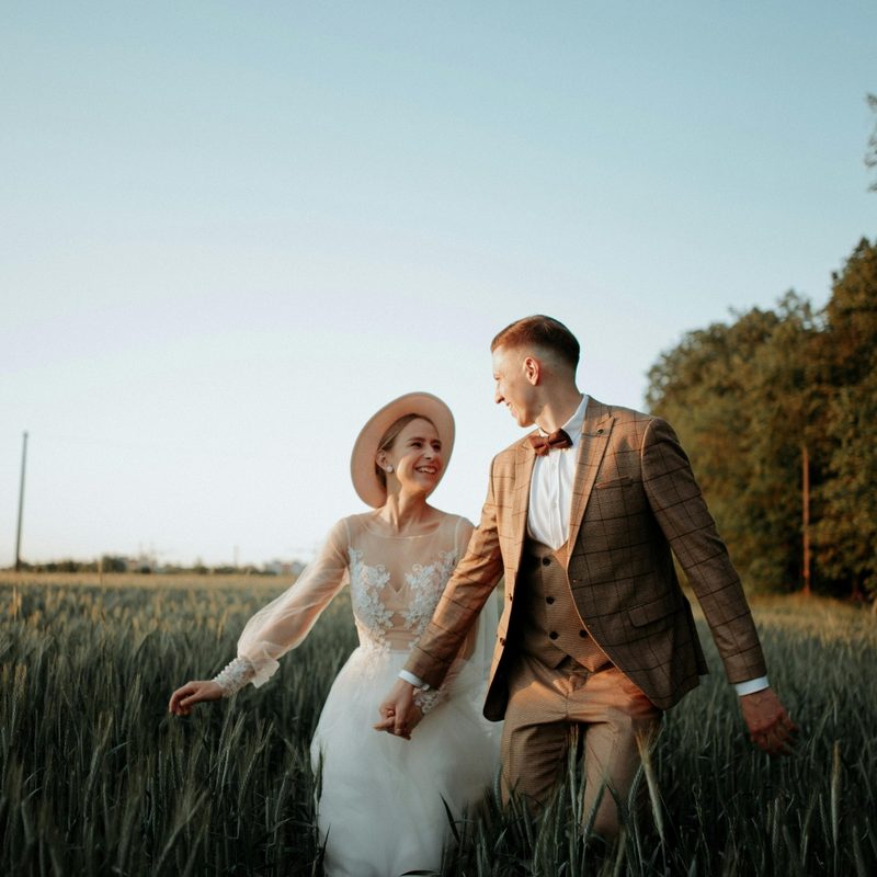 Couple in a field where he is wearing a brown suit