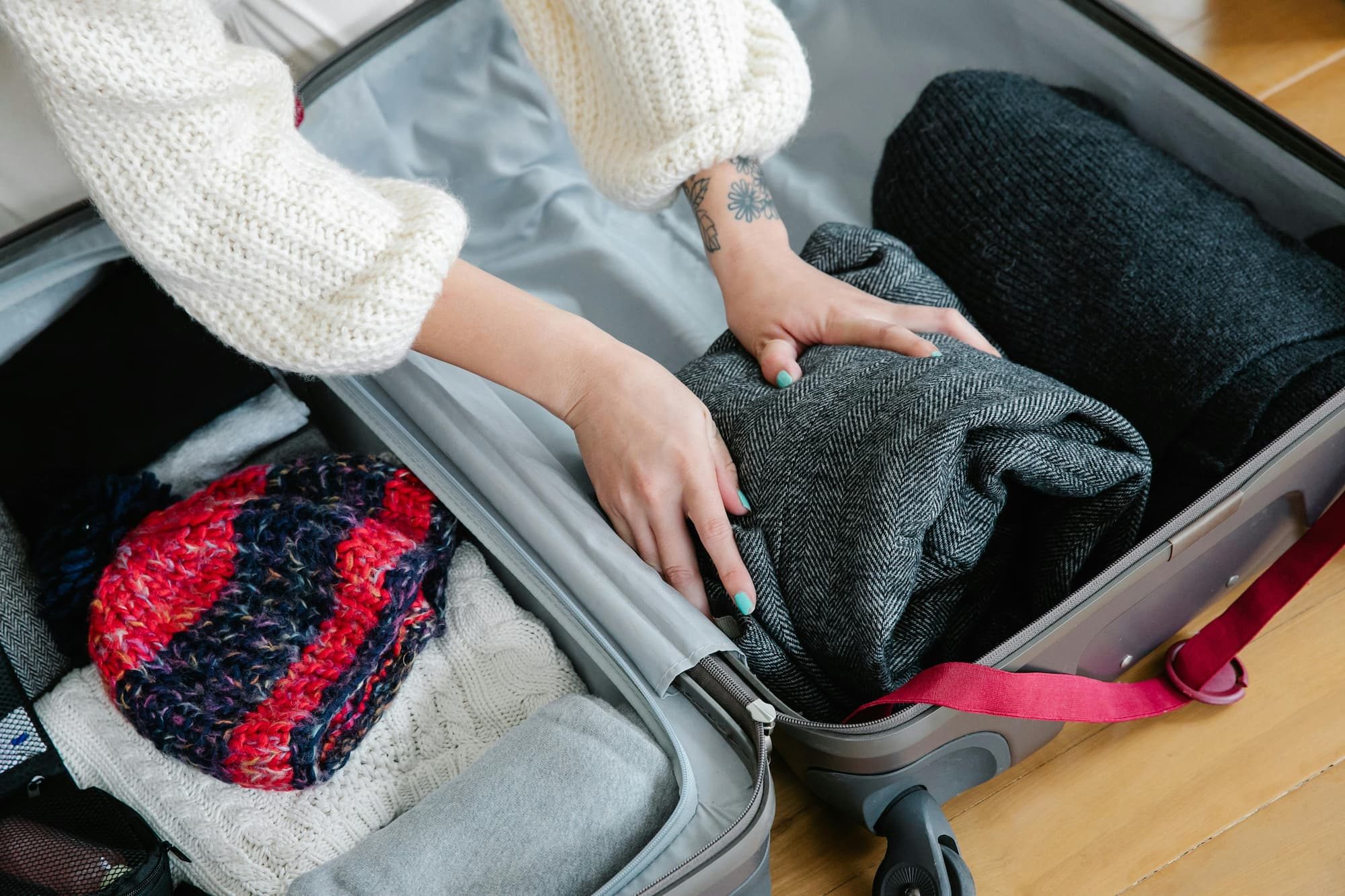 person putting folded clothes in luggage