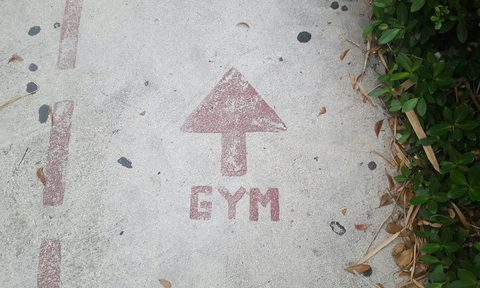 Gym sign on road in red concrete with arrow pointing to gym