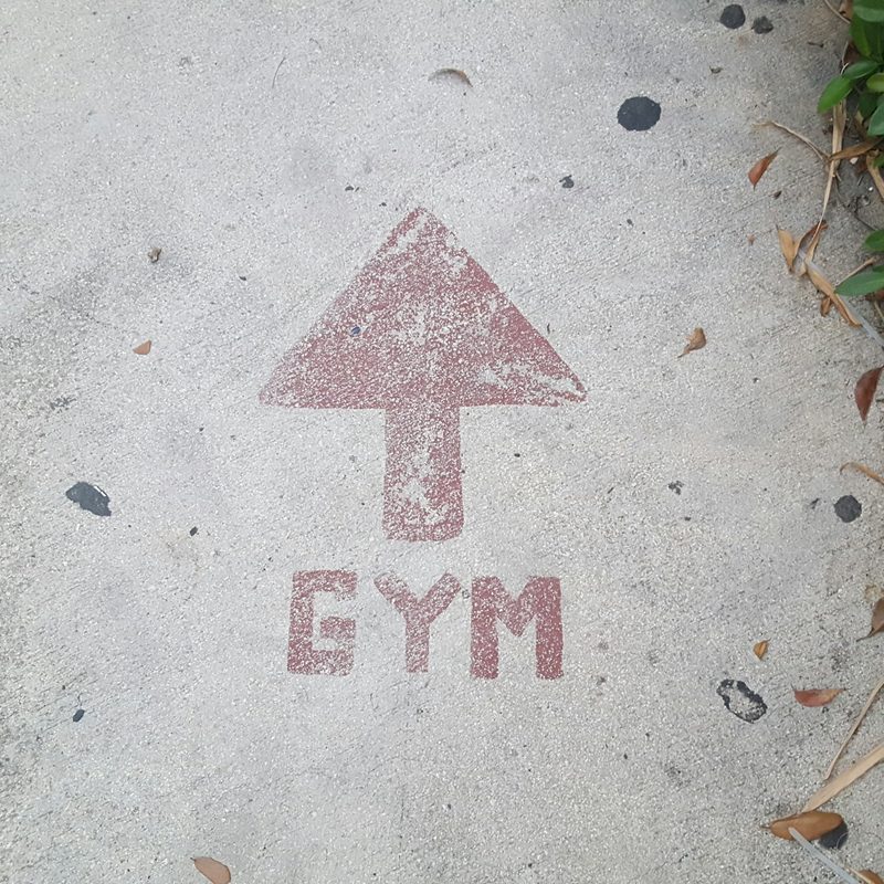 Gym sign on road in red concrete with arrow pointing to gym