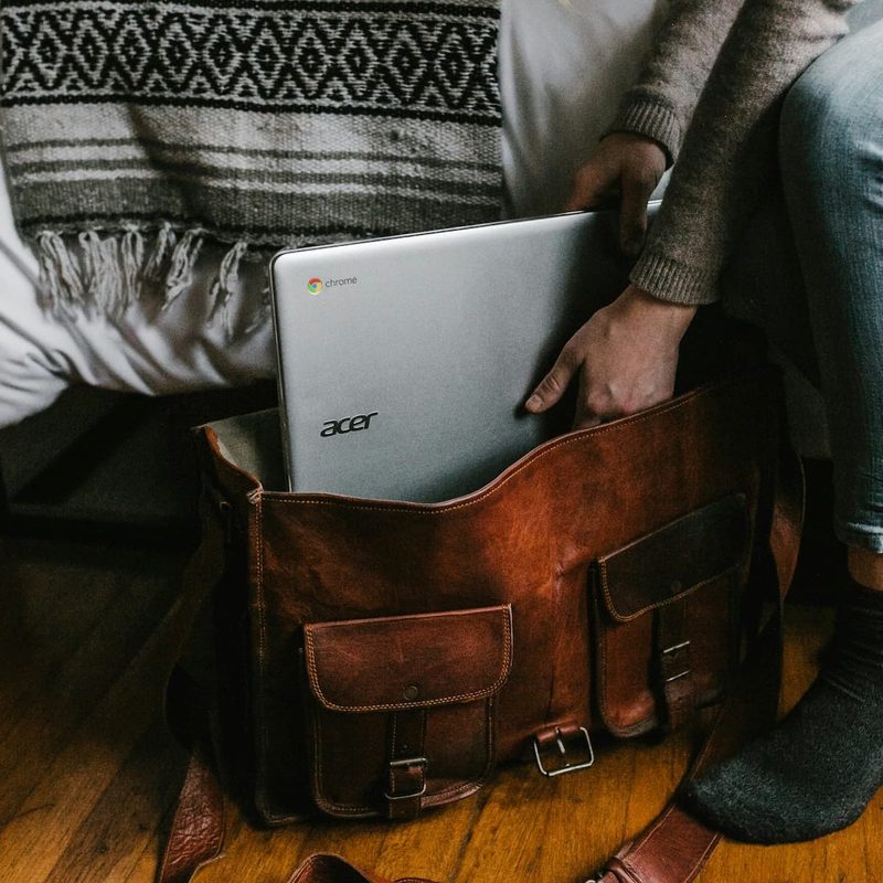 person packing a laptop in a bag