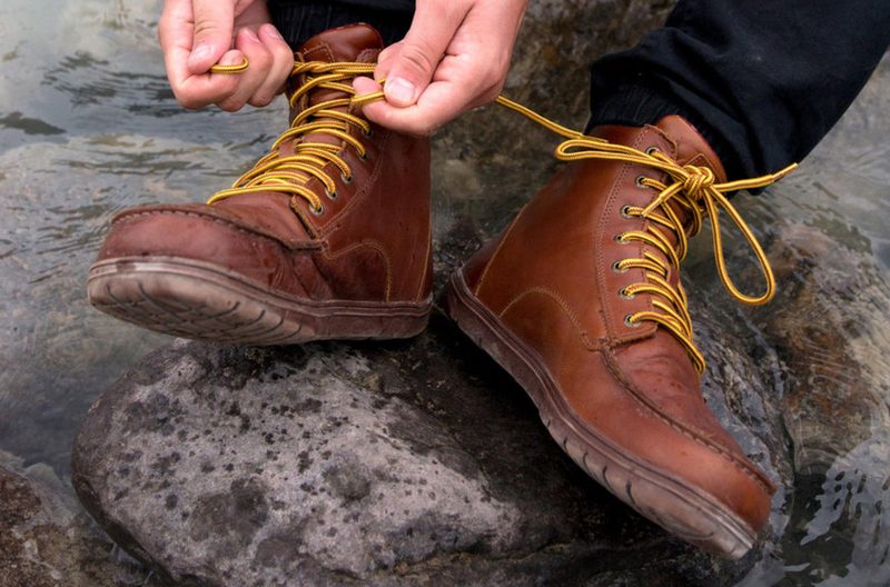 man tying red hiking boots