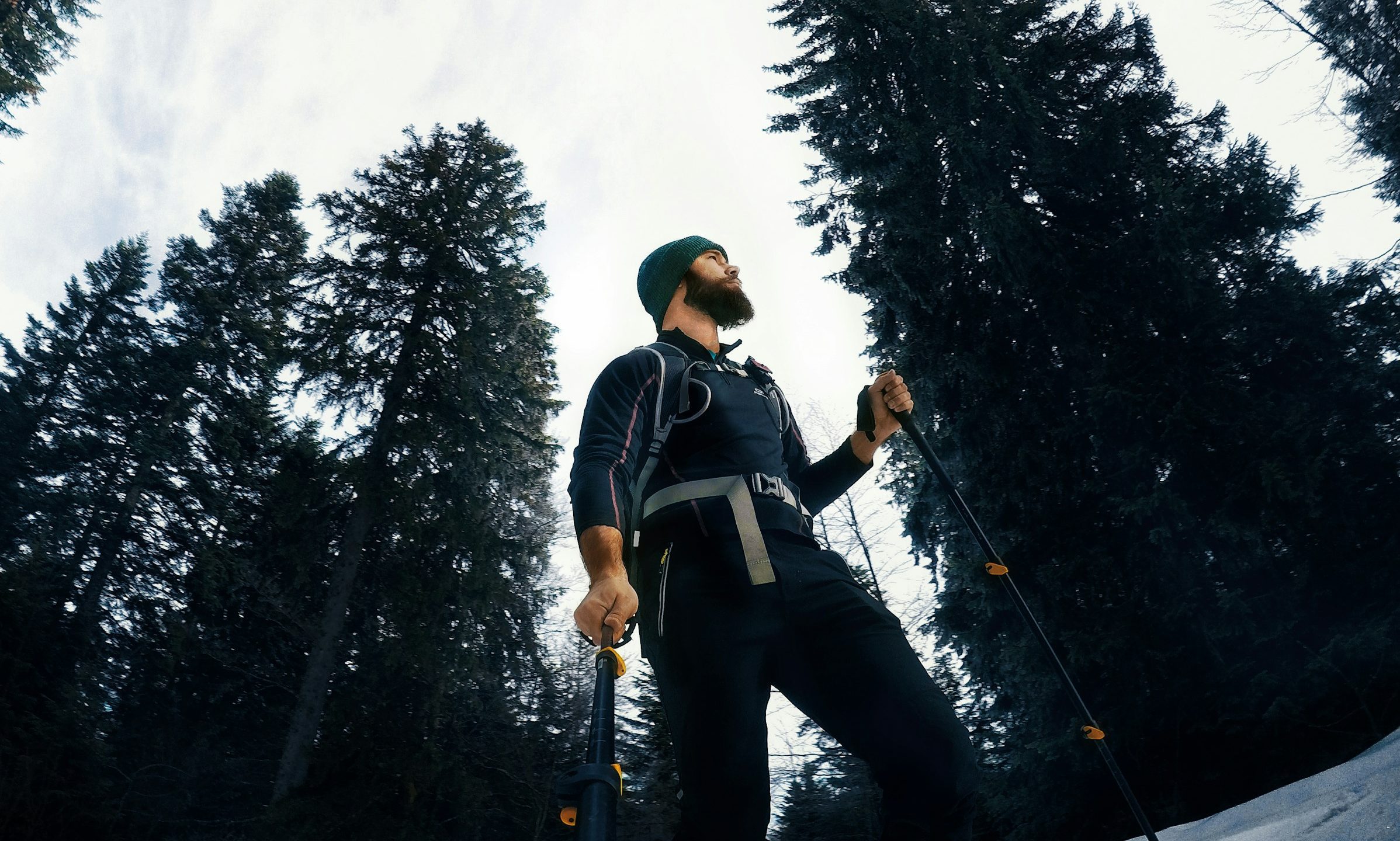 Man walking with Nordic walking poles outside by the trees wearing a hat