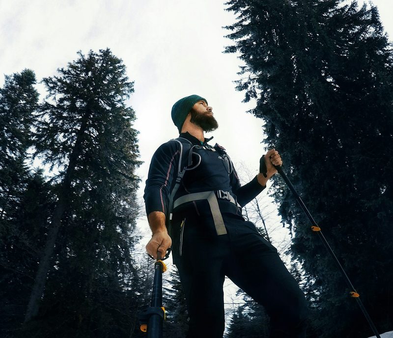 Man walking with Nordic walking poles outside by the trees wearing a hat