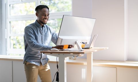 Man using adjustable height standing desk In office for good posture
