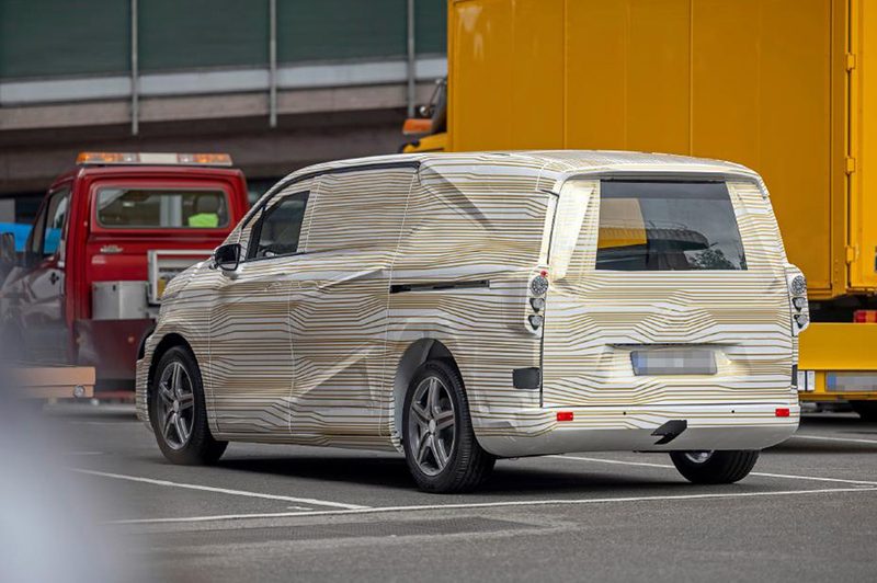 An electric Mercedes-Benz prototype van covered in heavy vehicle camouflage.