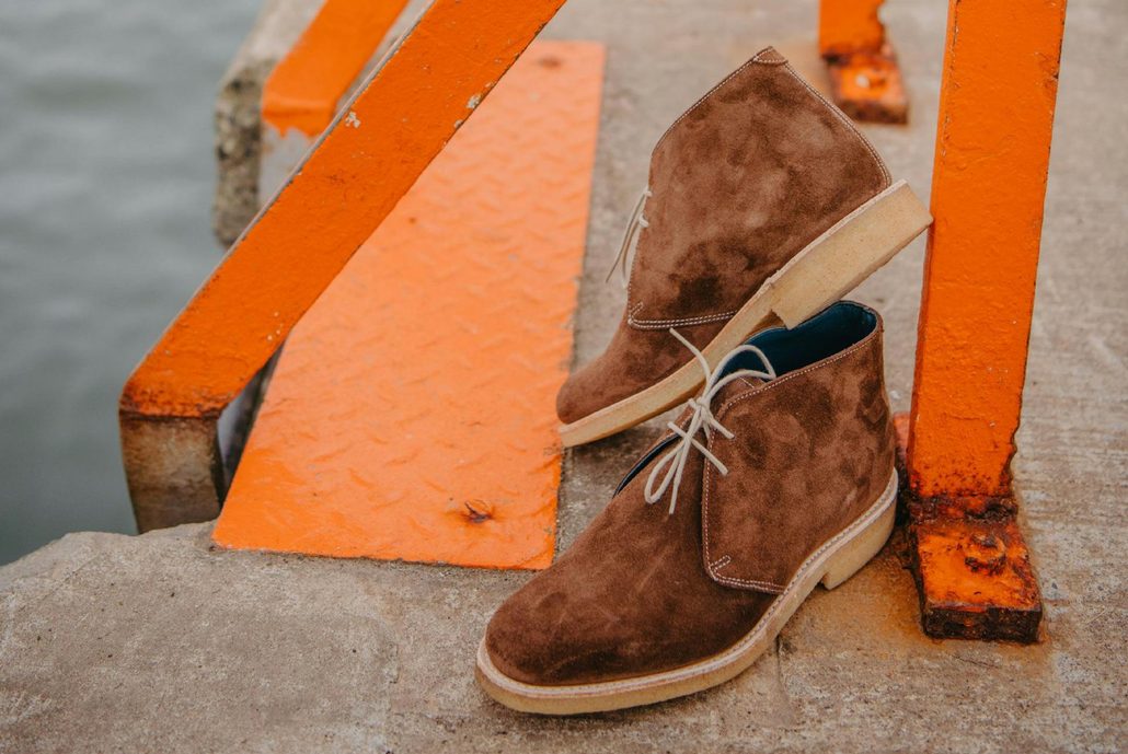 brown suede shoes sitting against concrete