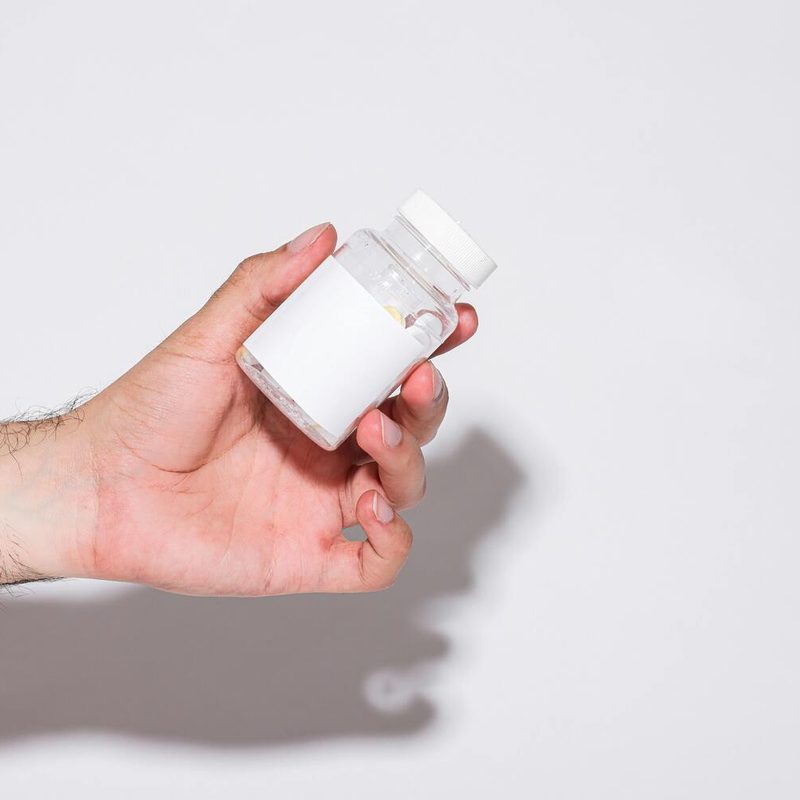 Man holding supplement bottle.