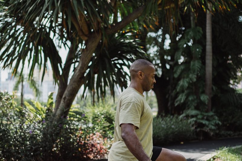 man doing walking lunge outside by palm tree