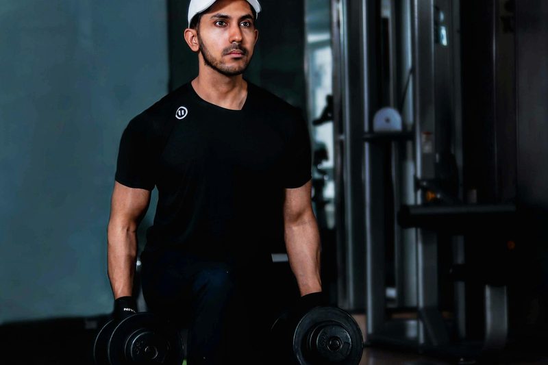 man wearing black t shirt and white hat doing walking lunges with dumbbells