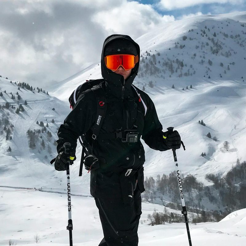 Man holding ski poles skiing standing by snowy mountain