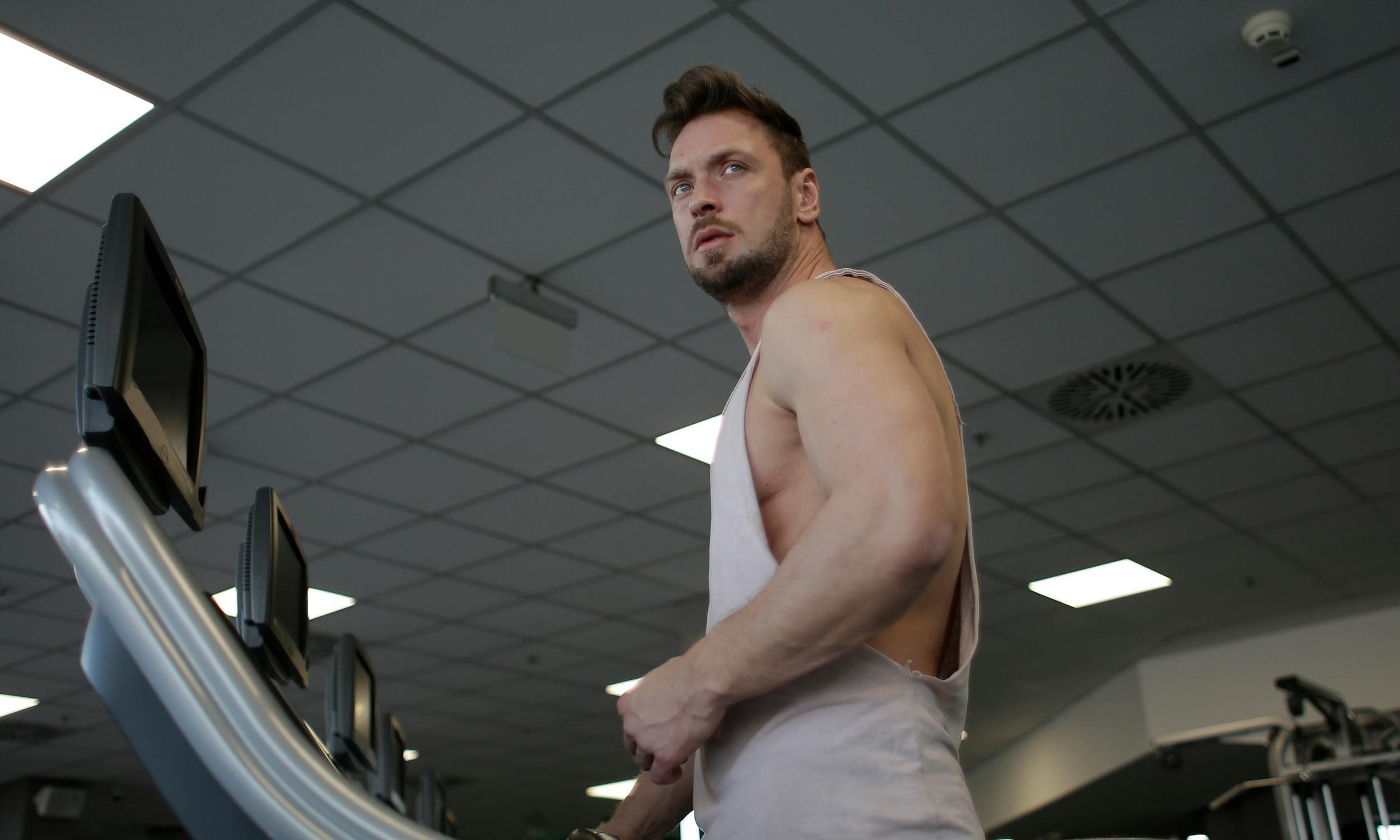 Man on treadmill with sleeveless shirt in gym