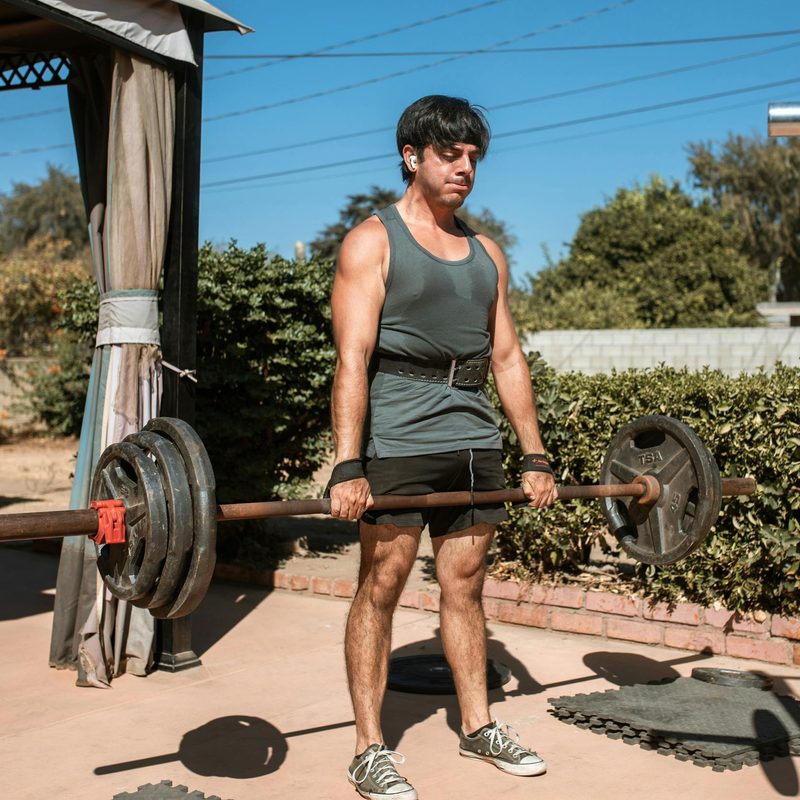 man deadlift barbell outside using lifting straps wrist strap