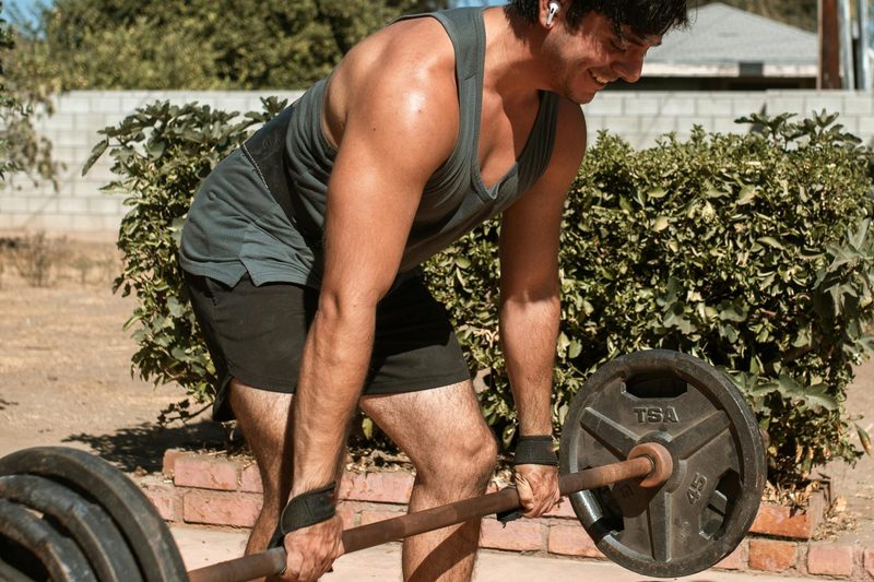 man leaning over to perform deadlift using lifting straps wrist strap