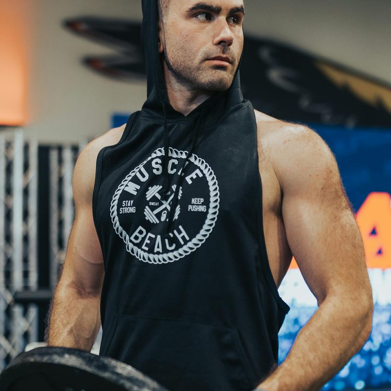man in gym wearing black sleeveless shirt with hood holding weight