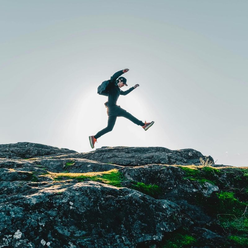 Man rucking, jumping, walking, backpacking with rucksack on rocks