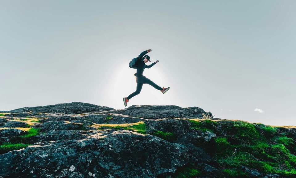 Man rucking, jumping, walking, backpacking with rucksack on rocks