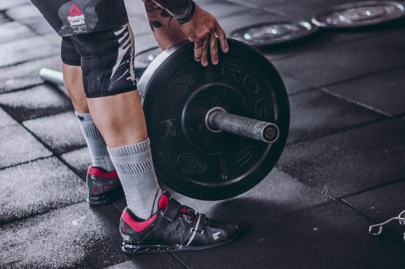 man holding barbell weight leaning down close up