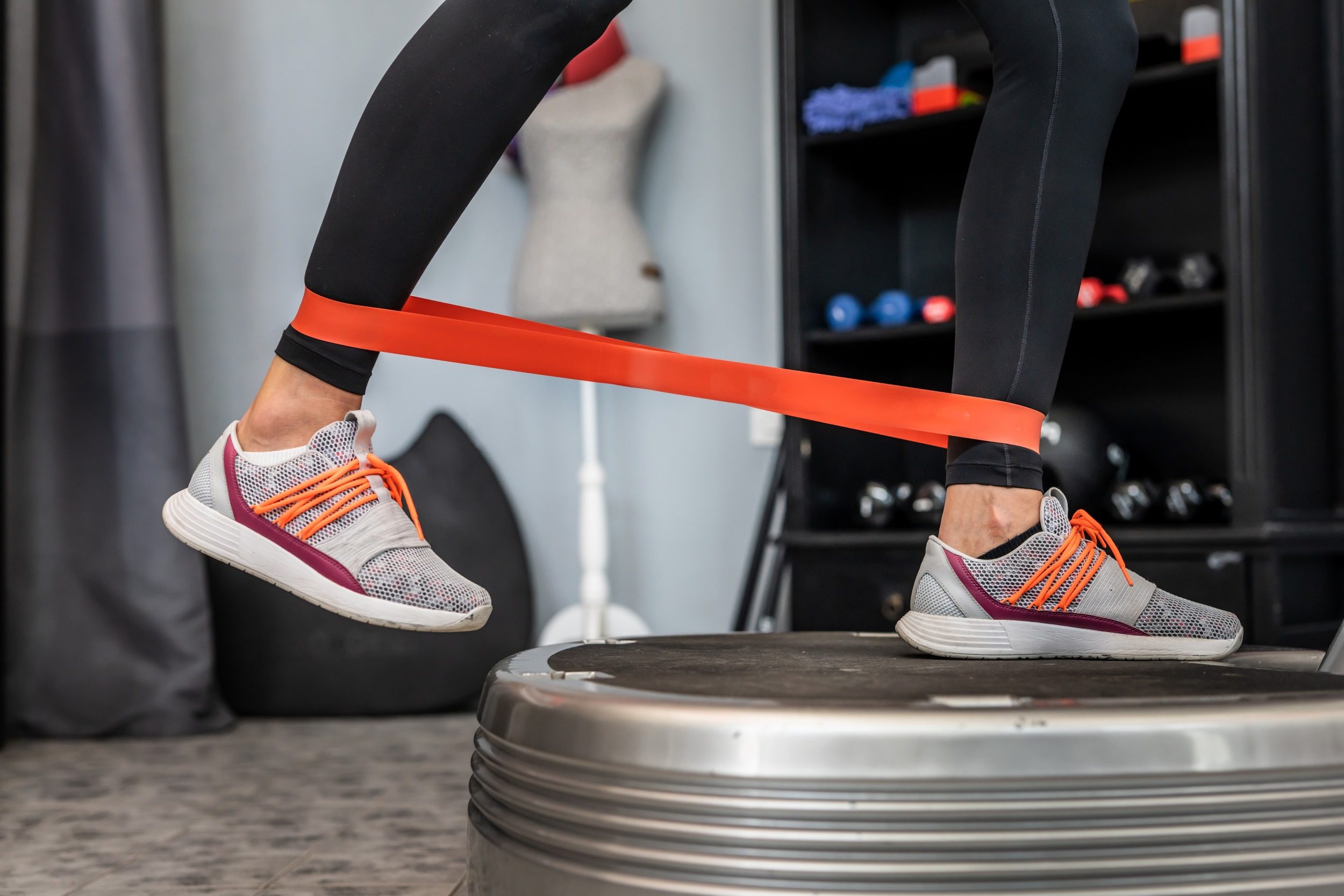 woman leg resistance band on vibration plate machine