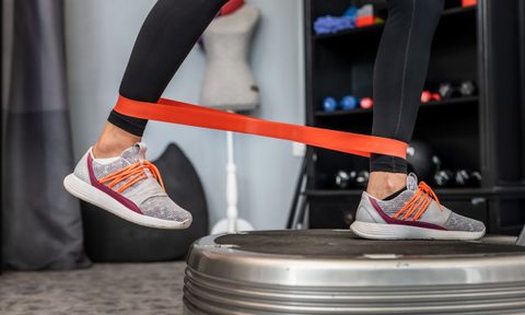 woman leg resistance band on vibration plate machine