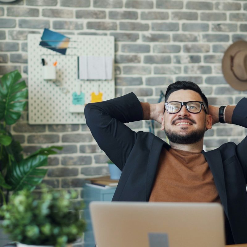 Man happy smiling at desk stretching arms positive