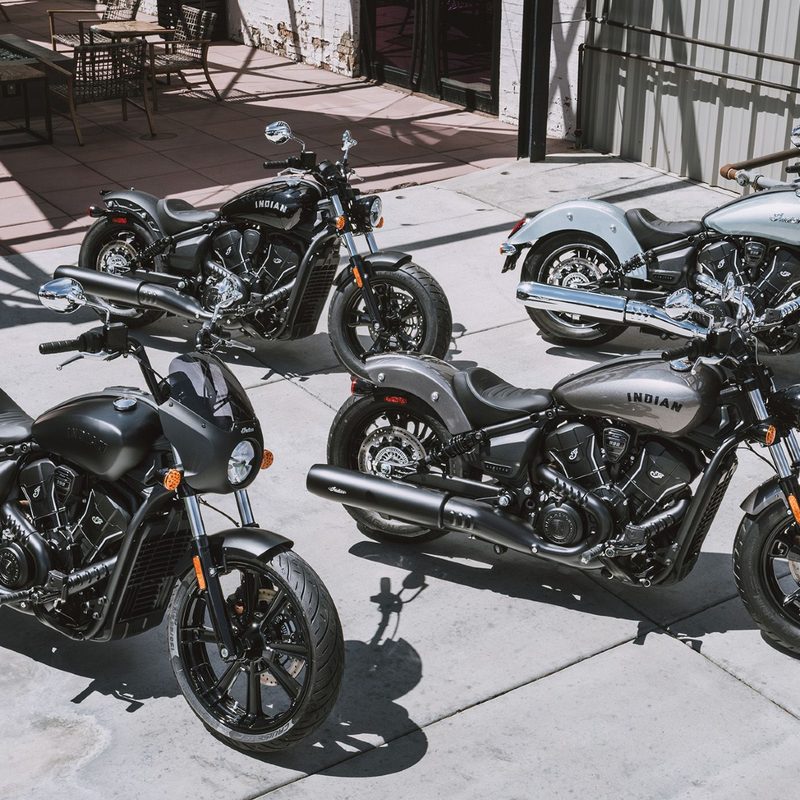 2025 Indian Motorcycle Scout Sixty model lineup of four models on a concrete patio outside a restaurant.