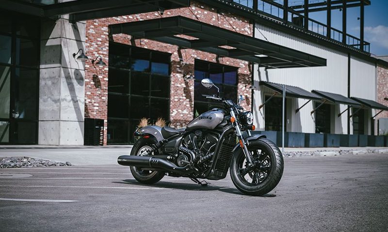 2025 Indian Scout Sixty Bobber parked on asphalt in front of a restaurant in a vacant parking lot.