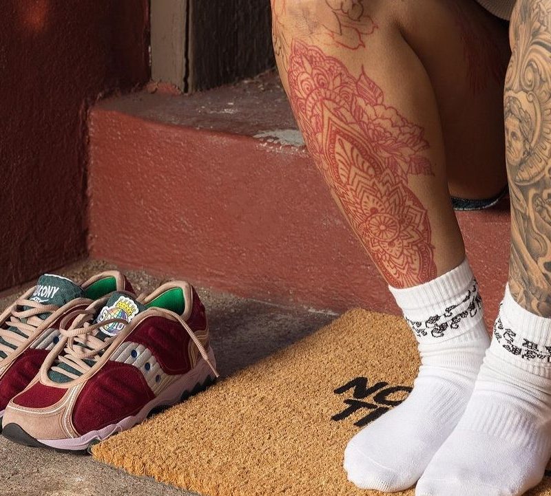 man sitting in socks next to pair of saucony shoes