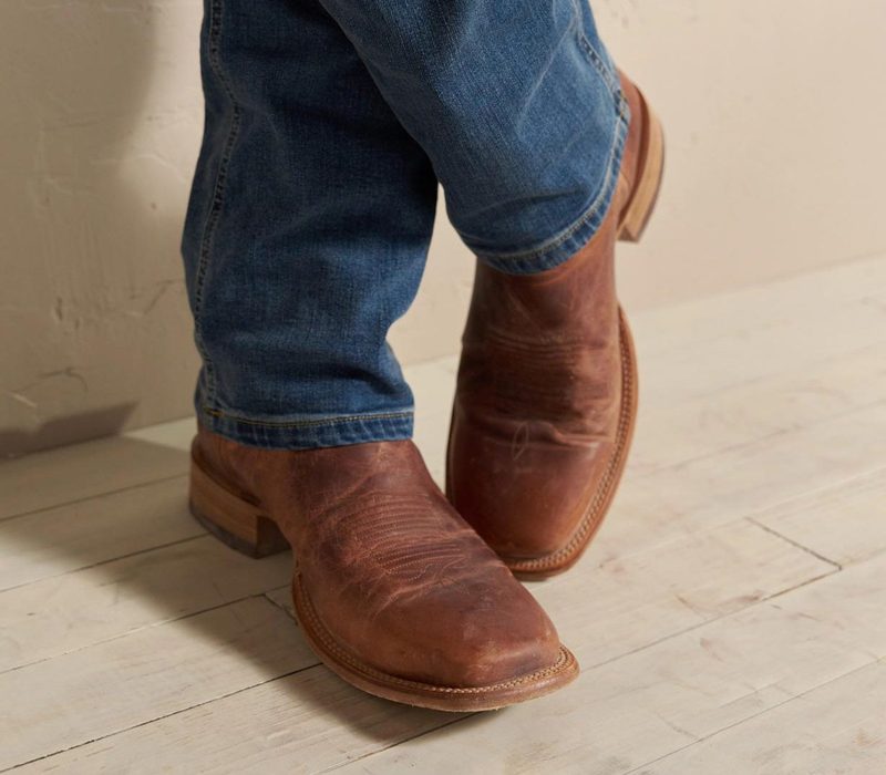 model wearing brown cowboy boots and blue denim jeans