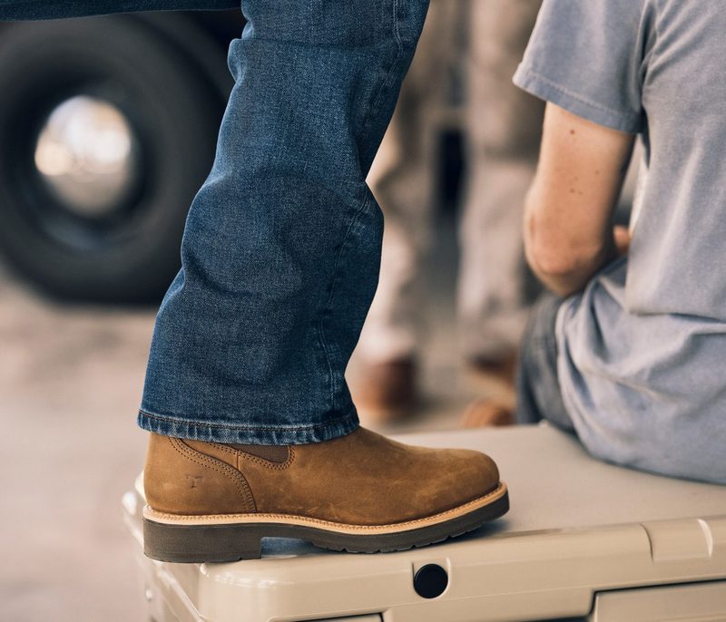 man wearing brown suede boots with blue jeans