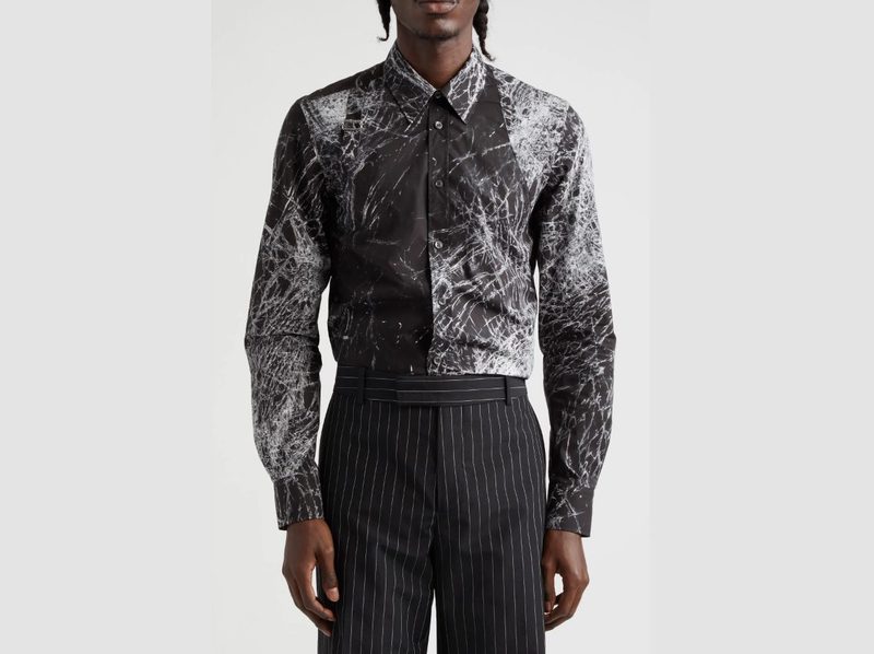 A man facing forward, wearing an Alexander McQueen Harness Smashed Screen Print Button-Up Shirt with nice pants.