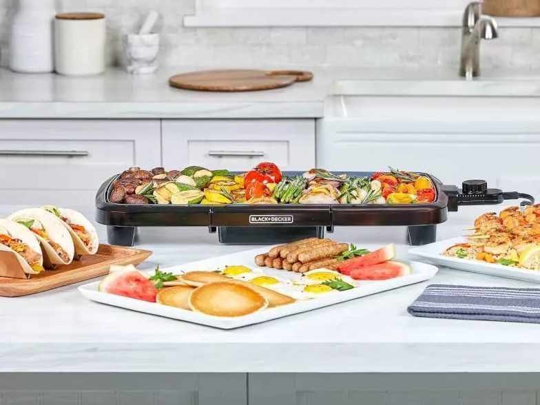 A side view of the Black+Decker 20-inch cast iron family griddle, surrounded by food.