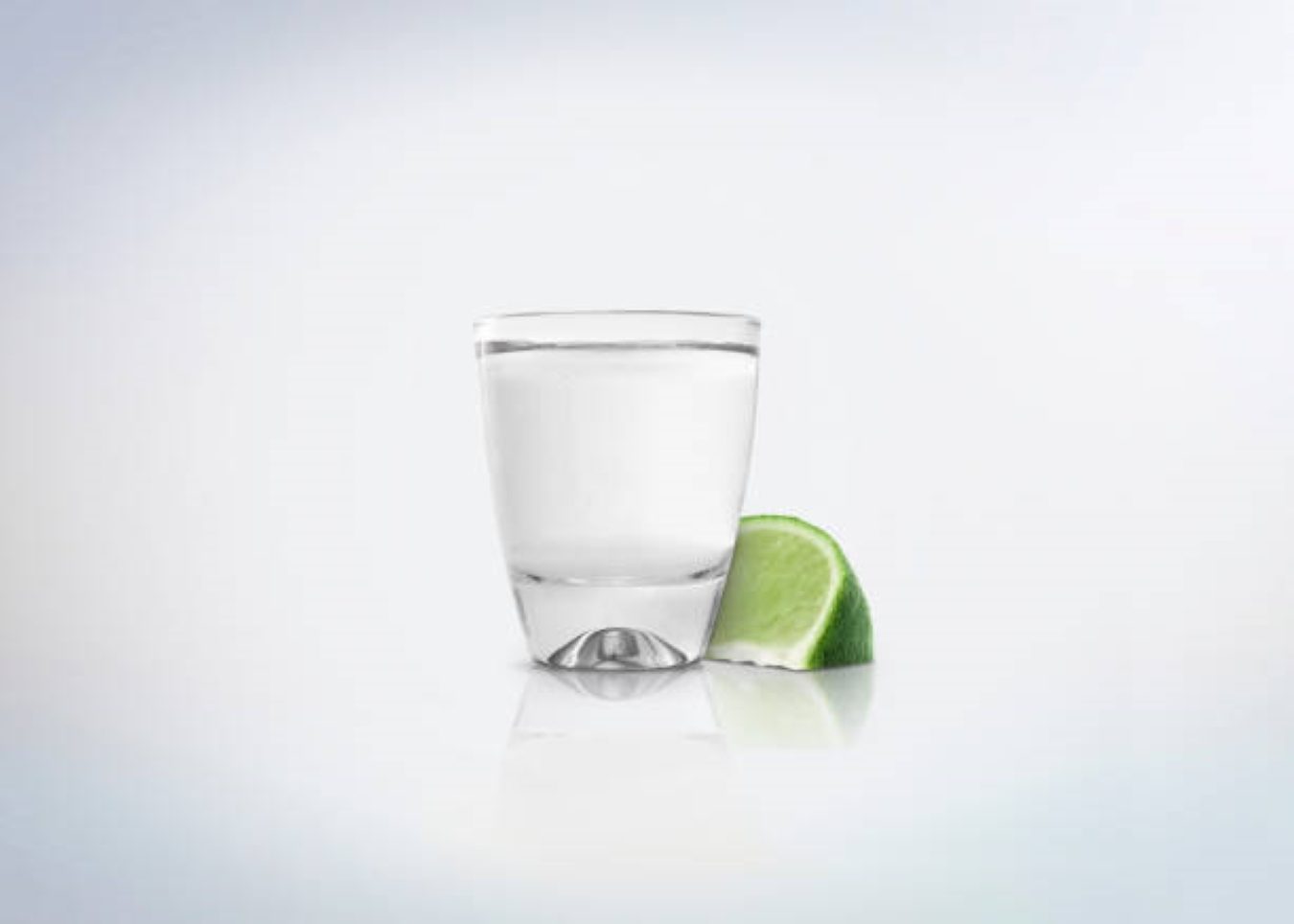 Tequila in shot glass next to a slice of lime