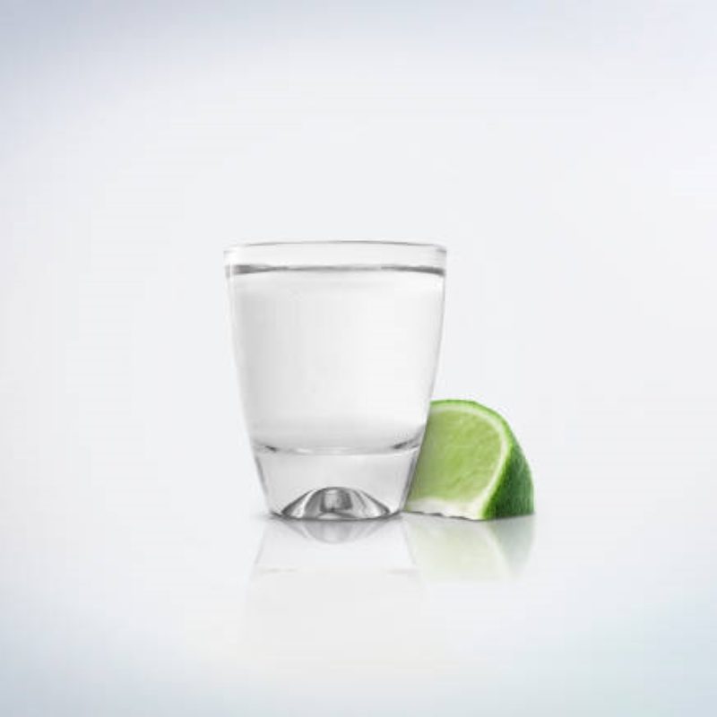 Tequila in shot glass next to a slice of lime