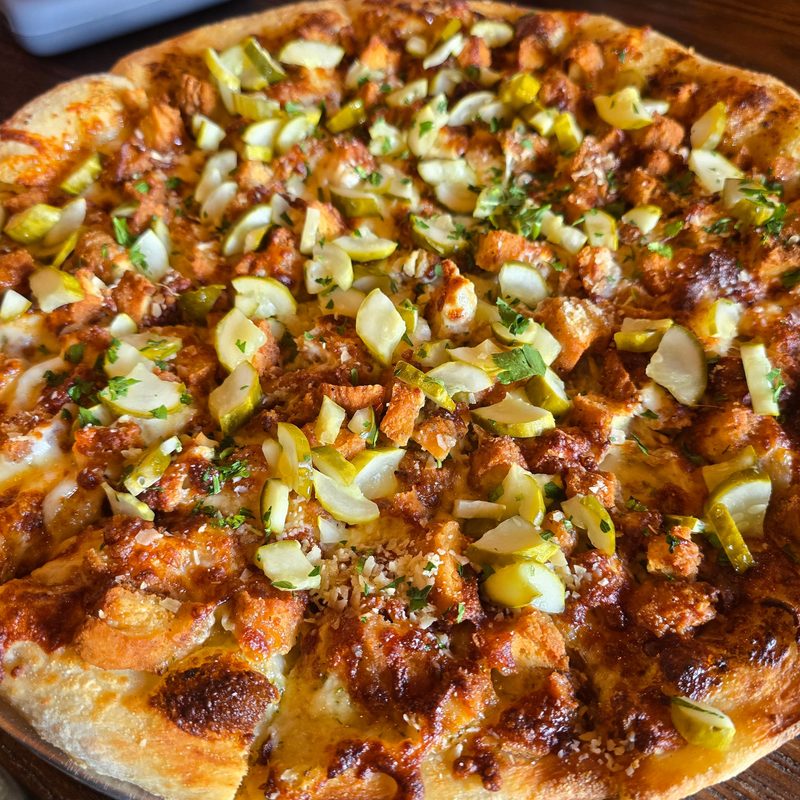 A full pickle and bacon pizza
