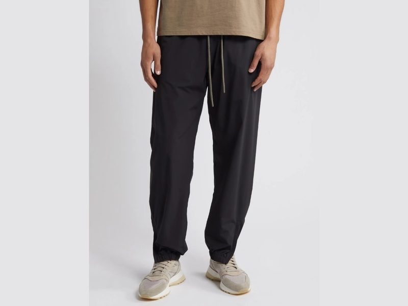 A man wearing Fear of God's Stretch Nylon Track Pants.