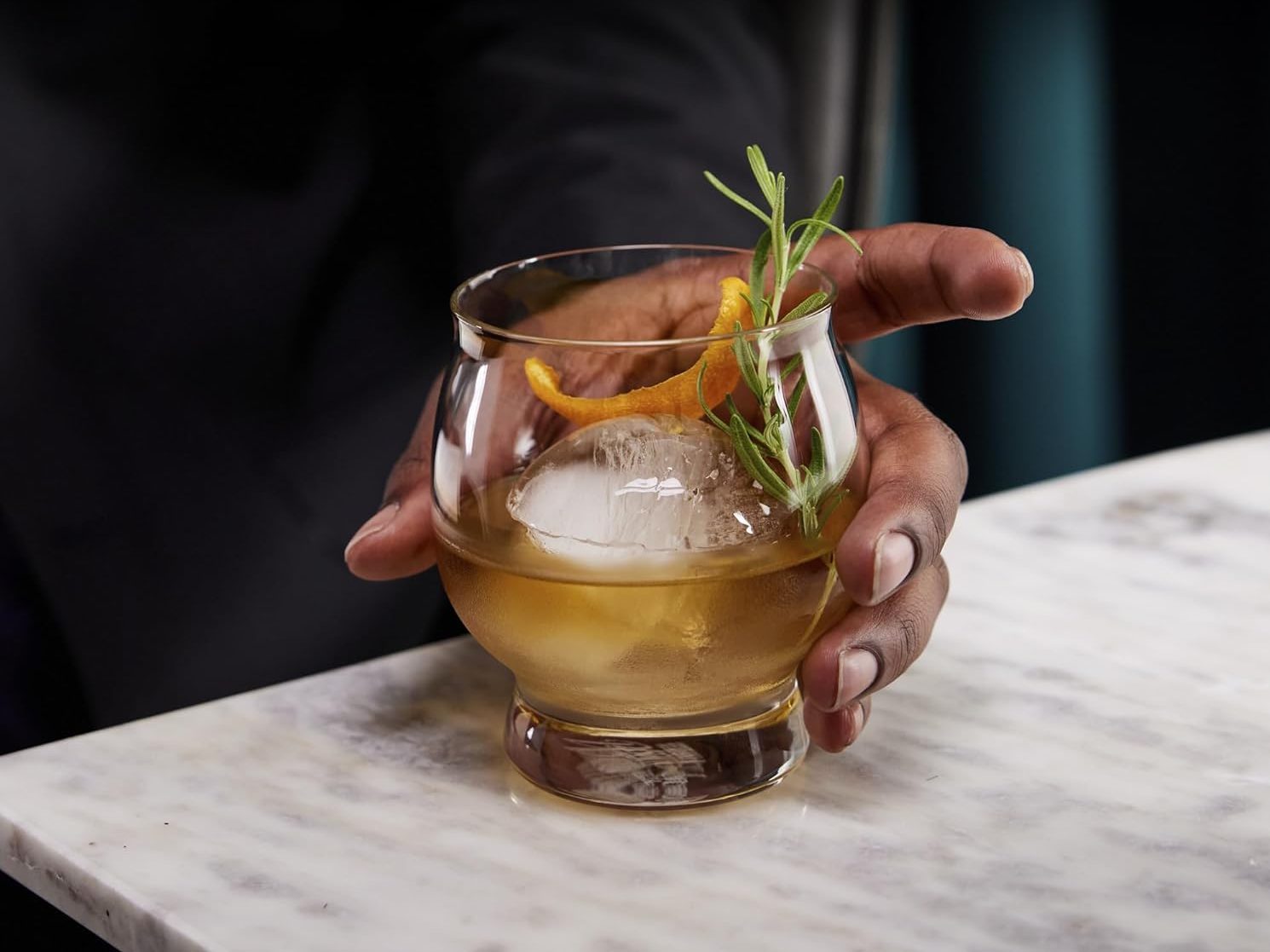 A man holding a mixed drink in a Libbey Signature Kentucky Whiskey Glass.