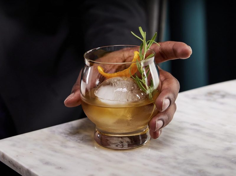 A man holding a mixed drink in a Libbey Signature Kentucky Whiskey Glass.