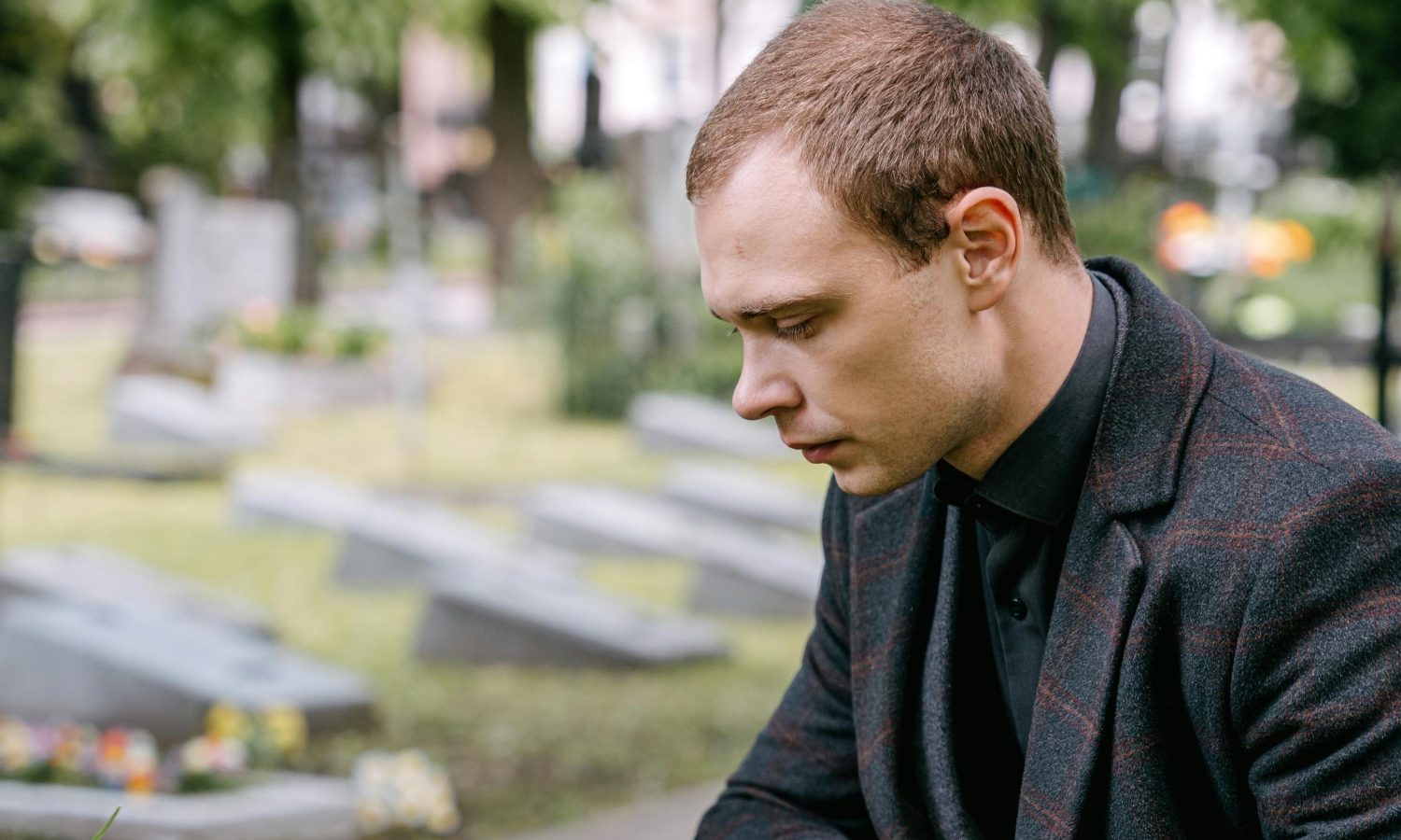 Man in coat and polo in cemetary