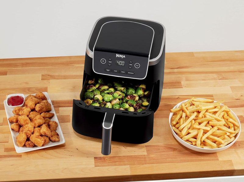 A meal made with a Ninja Air Fryer Pro 4-in-1 5-quart, it includes French fries, brussel sprouts, and chicken nuggets.