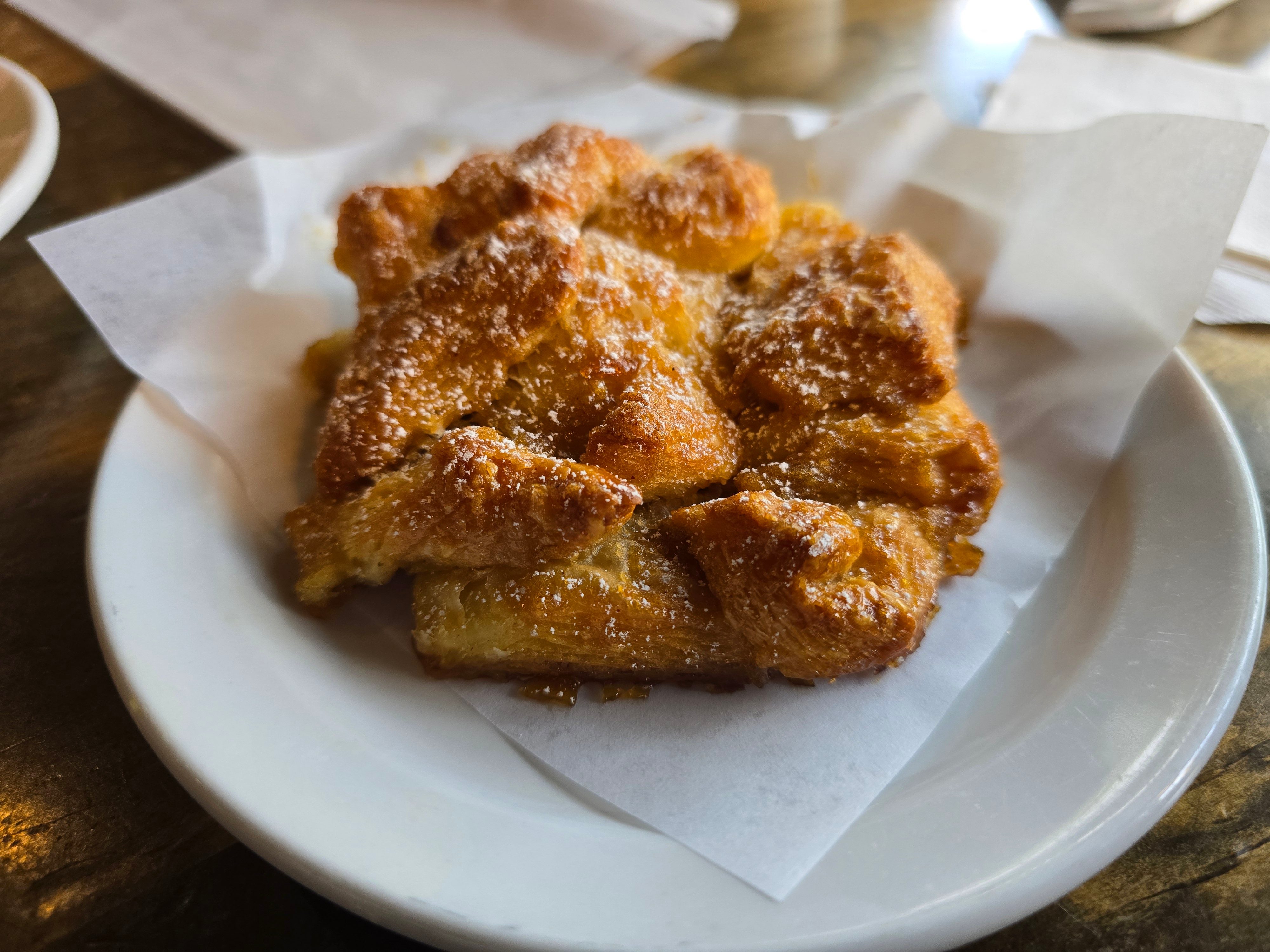 an apple fritter lightly dusted with powdered sugar