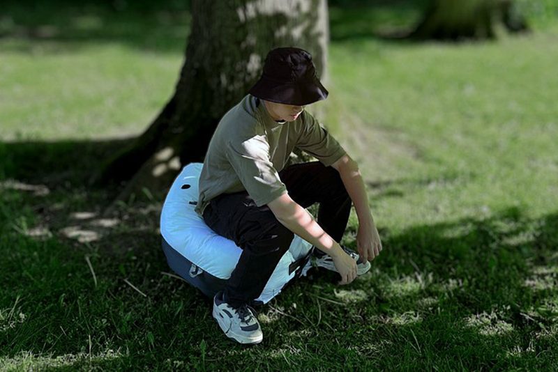 Man sitting on an AirPot inflatable toilet seat under a tree.